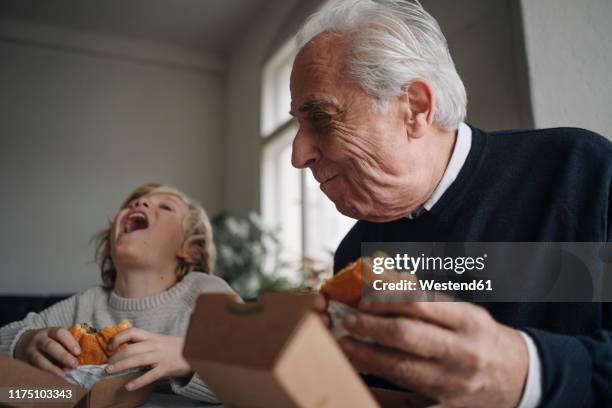 happy grandfather and grandson eating burger together at home - 孫子 個照片及圖片檔