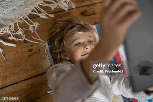 top view of boy lying on carpet using tablet - topnews foto e immagini stock