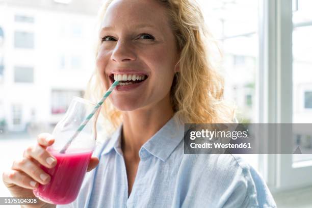 smiling blond woman drinking a smoothie - blended drink stock pictures, royalty-free photos & images