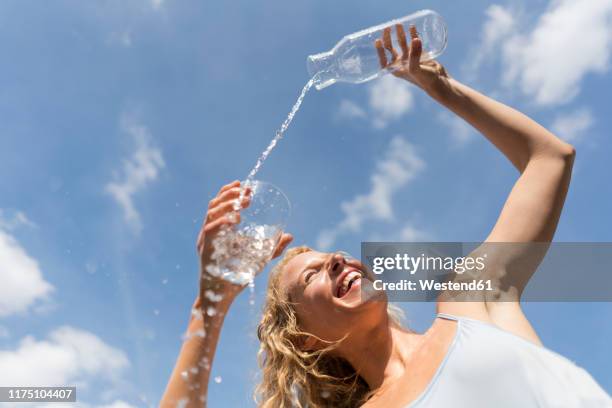 woman pouring water in a glass outdoors, low angle view - carafe stock pictures, royalty-free photos & images