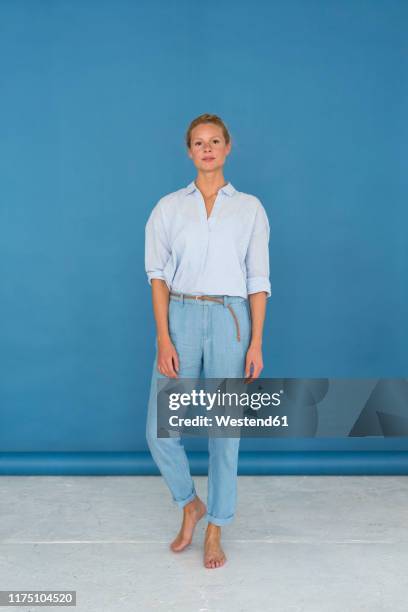 beautiful blond woman, blue background - white pants stock-fotos und bilder