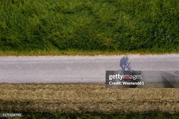 triathlete riding bicycle on country road, germany - country road aerial stock pictures, royalty-free photos & images