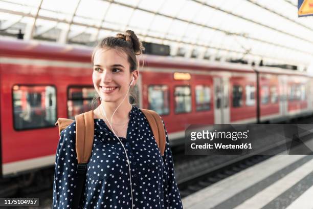 portrait of smiling young woman at the train station - station stock-fotos und bilder