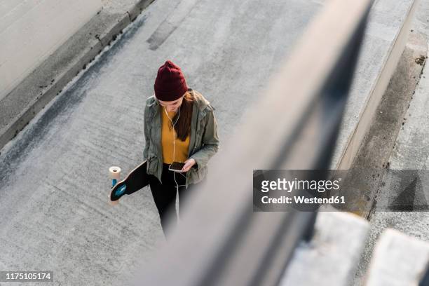 stylish young woman with skateboard and cell phone on parking deck - blickwinkel der aufnahme stock-fotos und bilder