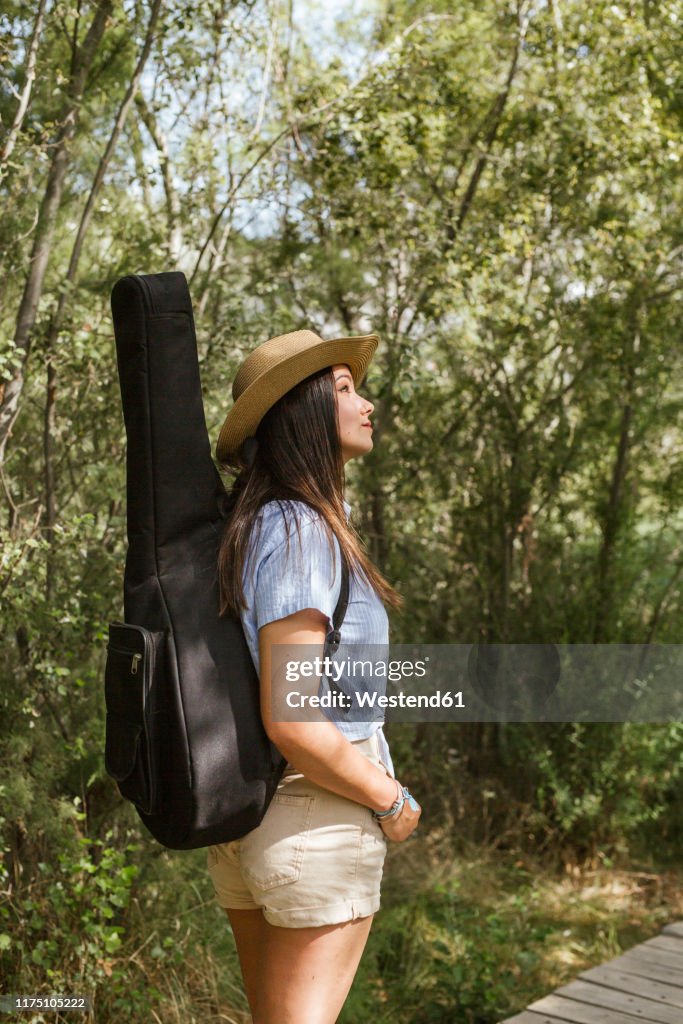 Young woman with guitar case looking up