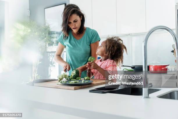 mother and daughter cooking in kitchen together cutting broccoli - kitchen bench top stock pictures, royalty-free photos & images