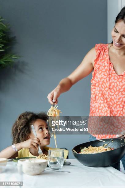 mother serving pasta meal for daughter sitting at dining table - the joys of eating spaghetti stock pictures, royalty-free photos & images