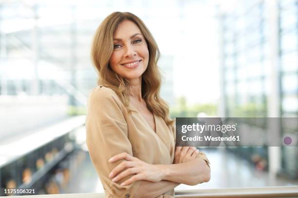 portrait of businesswoman with crossed arms at the airport - woman long brown hair stock pictures, royalty-free photos & images