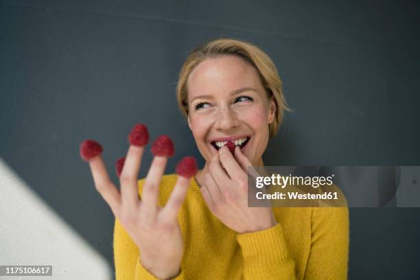 blond woman with raspberries on her fingers, laughing - berries and hand stock pictures, royalty-free photos & images