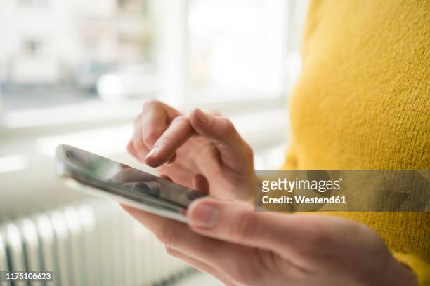 woman in yellow pullover, using smartphone - middelste deel stockfoto's en -beelden