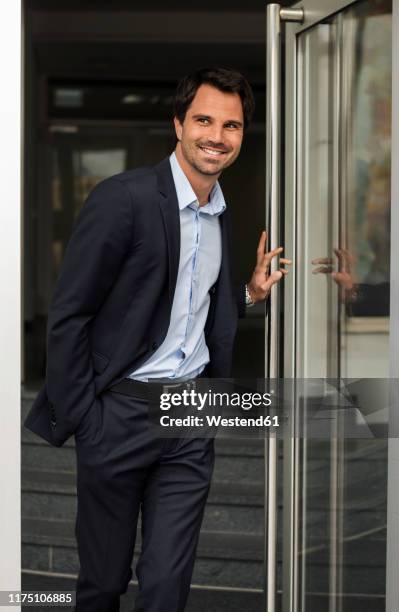 portrait of smiling businessman standing at open door - hemd aufreißen stock-fotos und bilder