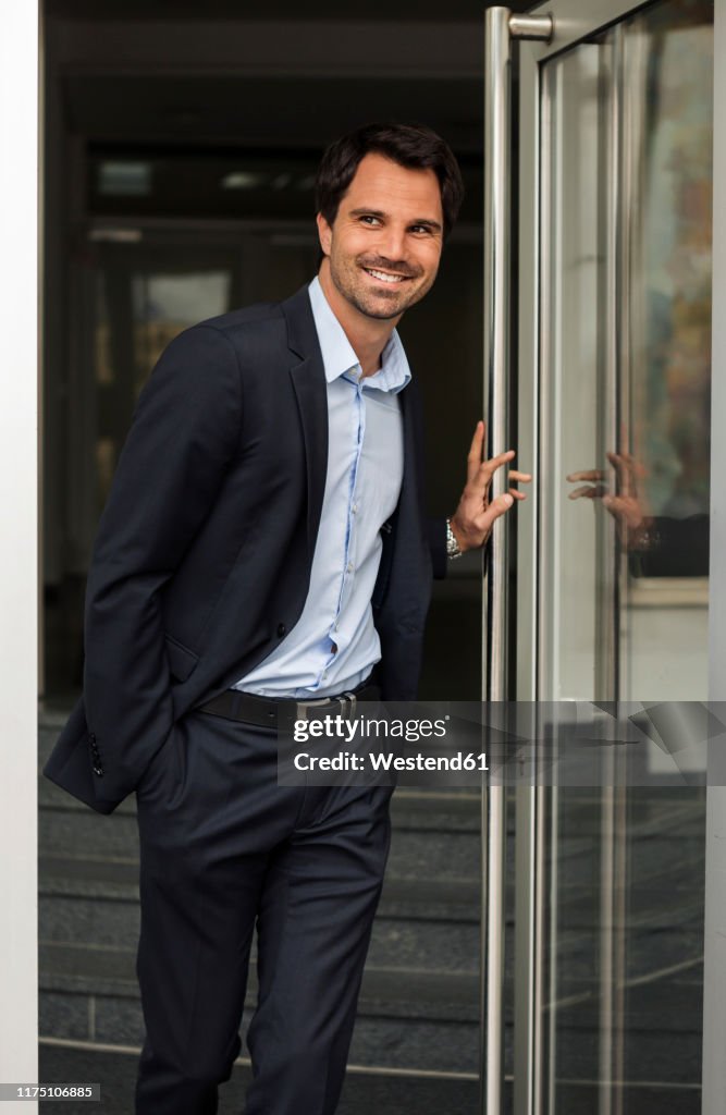 Portrait of smiling businessman standing at open door