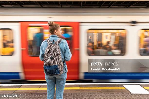 rear view of young woman at subway station with incoming train - london underground train stock pictures, royalty-free photos & images