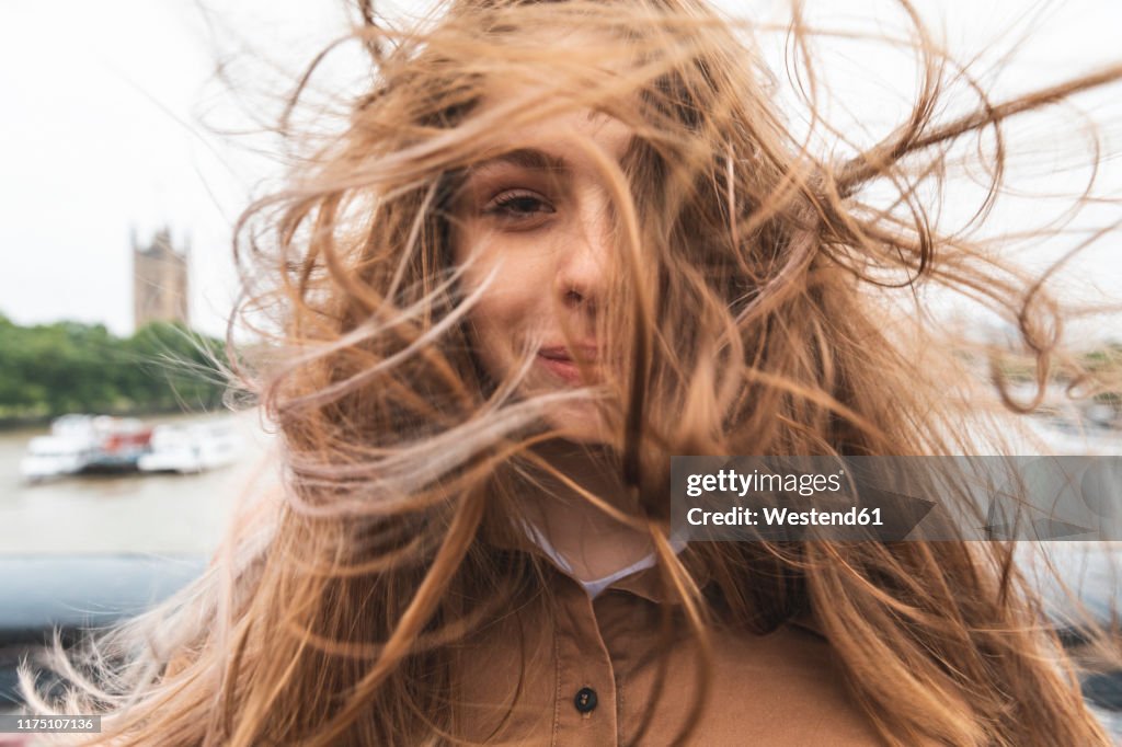 Portrait of smiling young woman with windswept hair, London, UK