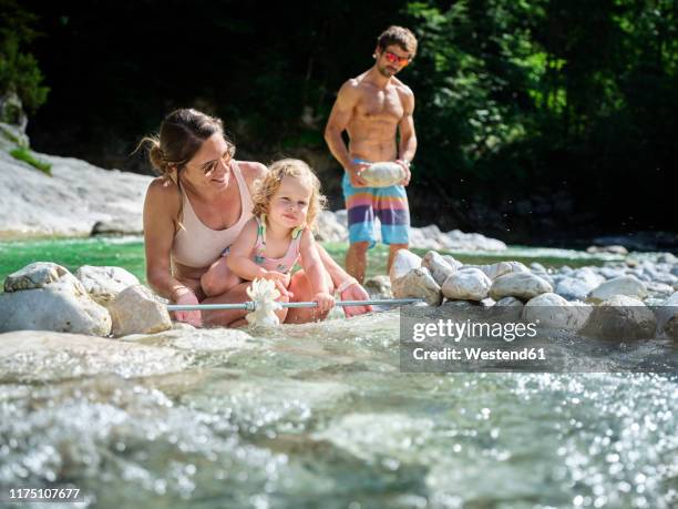 family with daughter fixing water wheel in a mountain stream - 水車 ストックフォトと画像