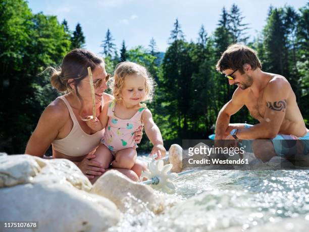 family with daughter fixing water wheel in a mountain stream - wasserrad stock-fotos und bilder