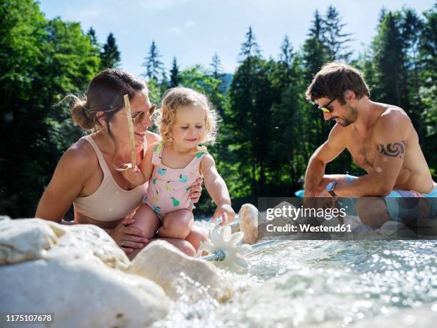 family with daughter fixing water wheel in a mountain stream - 水車 ストックフォトと画像