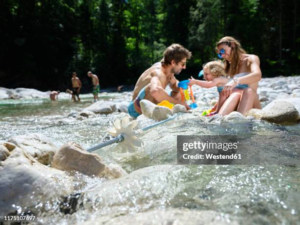 family with daughter playing in a mountain stream - water wheel stock pictures, royalty-free photos & images