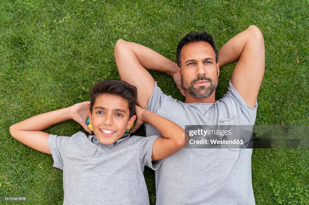 Father and son lying in grass together