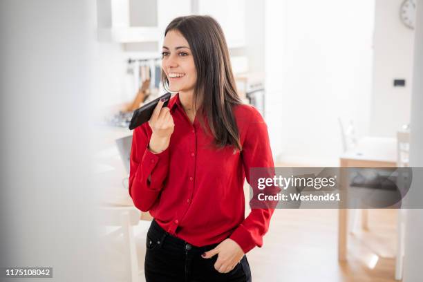 smiling young businesswoman using smartphone at home - red dress shirt stock pictures, royalty-free photos & images