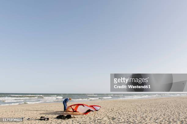 male surfer preparing a kite at the beach - kite surf stock-fotos und bilder