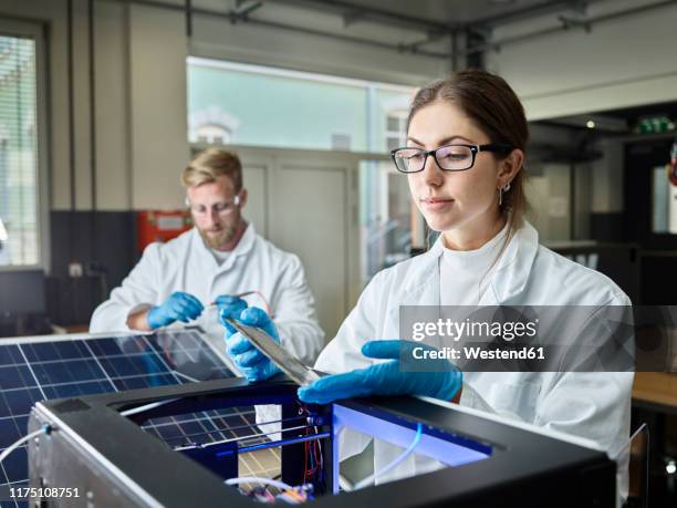 two technicians working on solar cell in lab - cleantech stock pictures, royalty-free photos & images