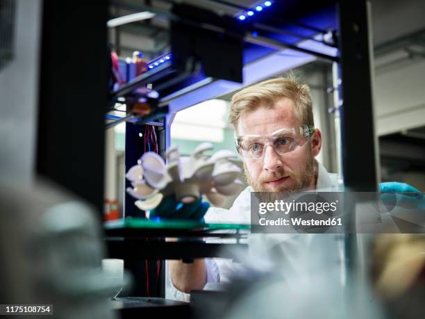 technician looking at turbine wheel being printed in 3d printer - modern laboratory stock pictures, royalty-free photos & images