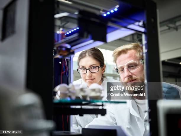 two technicians looking at turbine wheel being printed in 3d printer - stampante 3d foto e immagini stock