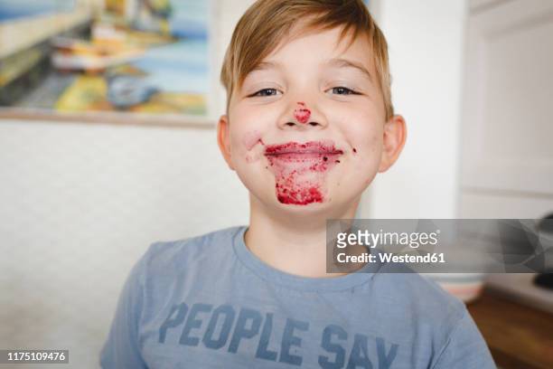 portrait of grinning boy with blueberry jam in his face - dirty face stock-fotos und bilder