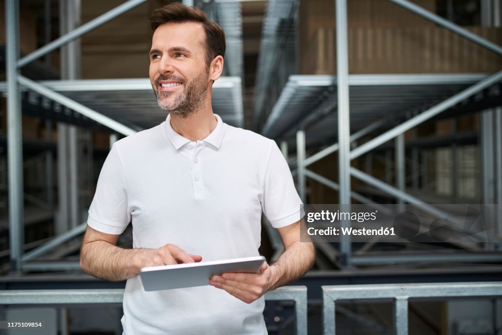 Smiling man using tablet in a factory