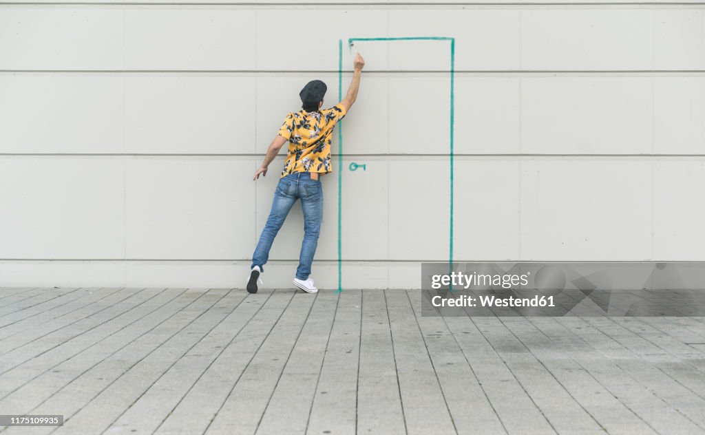 Digital composite of young man drawing a door at a wall