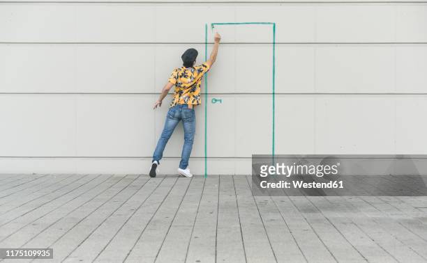 digital composite of young man drawing a door at a wall - acaso imagens e fotografias de stock