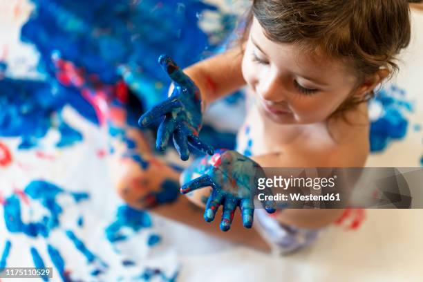 happy toddler girl playing with finger paint - manos pintadas fotografías e imágenes de stock