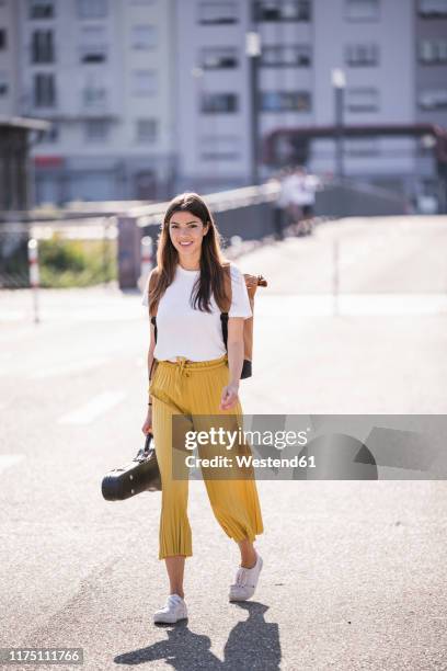 young woman carrying violin case walking on the street - young women walking stock pictures, royalty-free photos & images