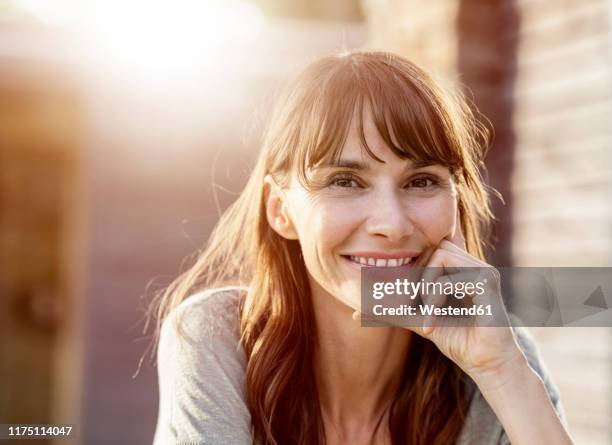 portrait of smiling brunette woman in backlight - older woman with brown hair stockfoto's en -beelden