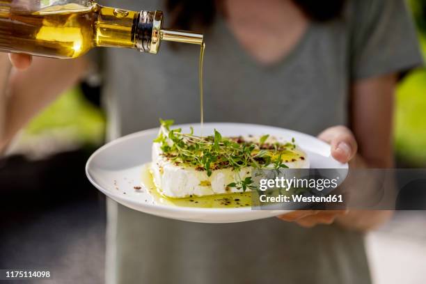 close-up of woman pouring olive oil over sheep cheese on plate - mediterranean food stockfoto's en -beelden