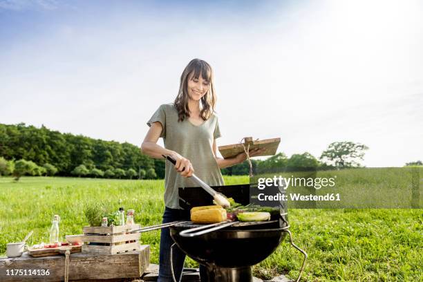 smiling woman preparing vegetable on barbecue grill - terraced field stockfoto's en -beelden