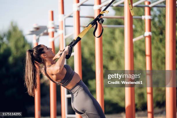 young woman doing workout on calisthenics bars - suspension training stock pictures, royalty-free photos & images