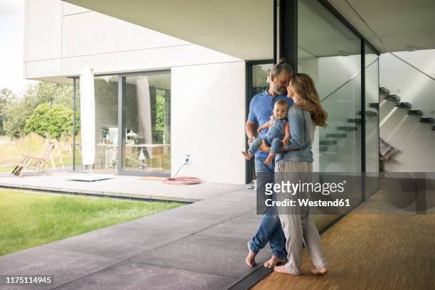 family of three standing at the window at home - family wealth stock pictures, royalty-free photos & images
