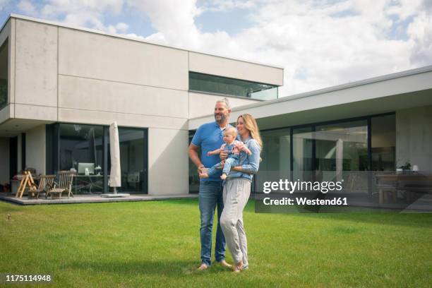 family of three standing in garden of their home - mom children standing no father stock-fotos und bilder