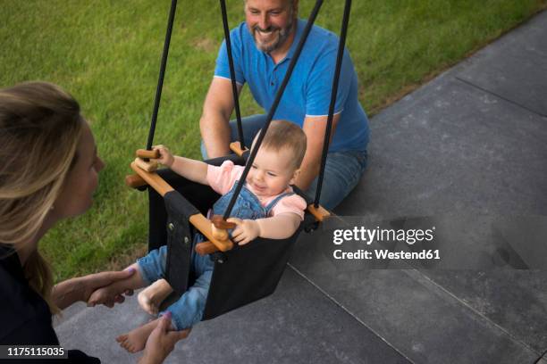 happy family with baby girl in a swing - couple swinging stock pictures, royalty-free photos & images