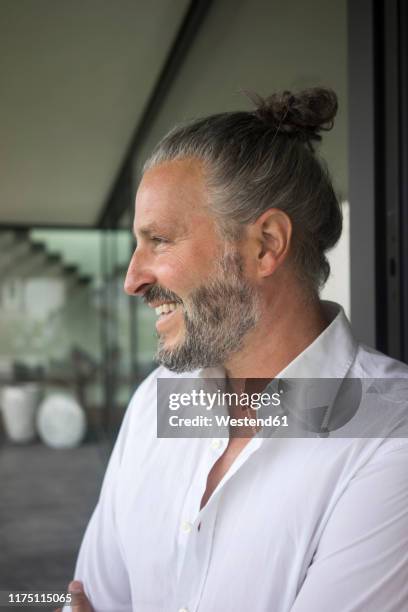 portrait of happy mature man with hair bun - man bun stock pictures, royalty-free photos & images