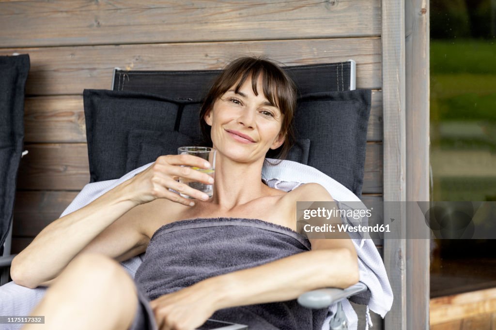 Portrait of woman relaxing on a lounge holding glass of water