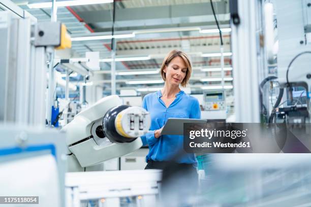businesswoman with tablet at assembly robot in a factory - roboterarm stock-fotos und bilder
