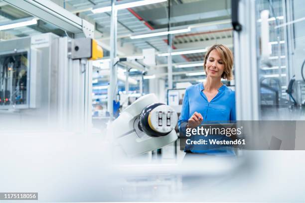 businesswoman with tablet at assembly robot in a factory - halle gebäude stock-fotos und bilder