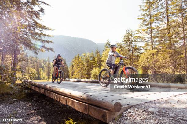 mother and daughter riding e-mountain bikes in the mountains - e sport stock pictures, royalty-free photos & images