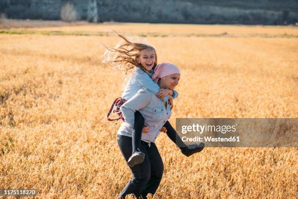 a woman with cancer carrying her daughter on her back, laughing - cancerland 2019 bildbanksfoton och bilder