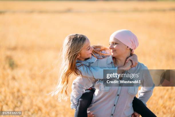 a woman with cancer carrying her daughter on her back, face to face - cancerland 2019 bildbanksfoton och bilder