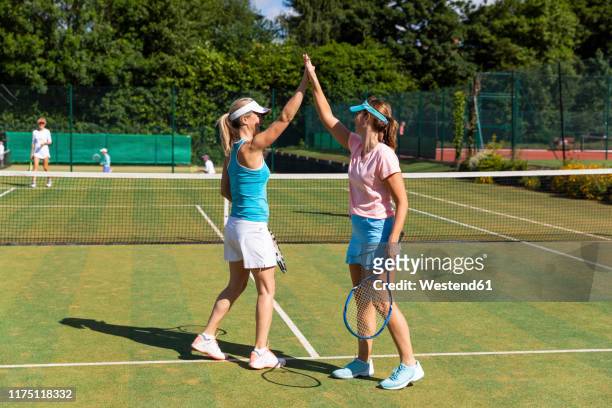 happy mature women celebrating after tennis match - doubles stock pictures, royalty-free photos & images