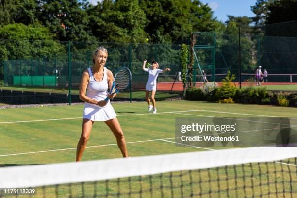 mature women during a tennis match on grass court - doubles stock pictures, royalty-free photos & images